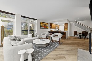 A modern living room with a sofa, chairs, a coffee table, and a kitchen area in the background. - Elegant Penthouse Connected to Grand Hyatt Vail Resort & Spa (Vail)