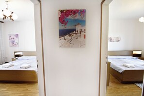 Ein Hotelzimmer mit zwei Betten, einem Bild mit einer Küstenansicht und Holzboden.
