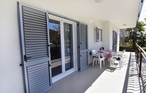 Ein Balkon mit Tisch und Stühlen, einer Schiebetür und einer weißen Wand.