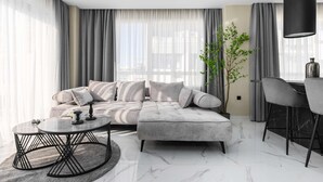 En moderne stue med en modulsofa, et rundt sofabord, et sofabord, en potteplante og en sort lampe.