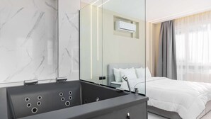 Et moderne hotelværelse med badeværelse i marmor, en seng og et stort spejl.