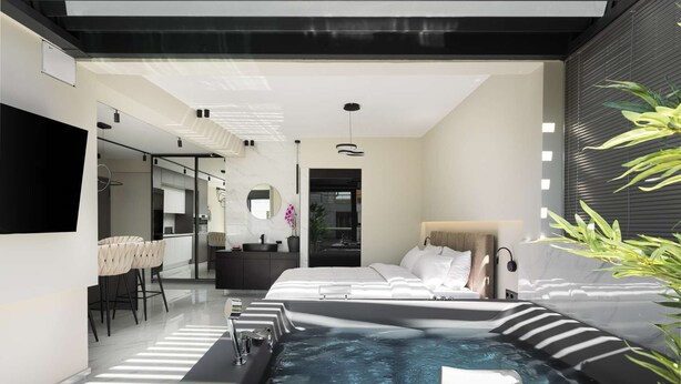 Ett modernt hotellrum med en stor säng, en liten sittgrupp, ett badrum och en privat utomhusavdelning med bubbelbadkar.