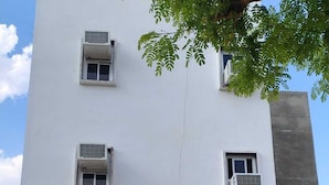 A building with multiple air conditioning units, a prominent sign for 'HOTEL ADITYA,' and a large glass entrance. - Hotel Aditya Bikaner (Bikaner)