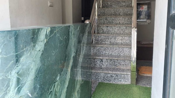 A staircase with a marble wall and a green carpet leading up to a door. - Hotel Aditya Bikaner (Bikaner)