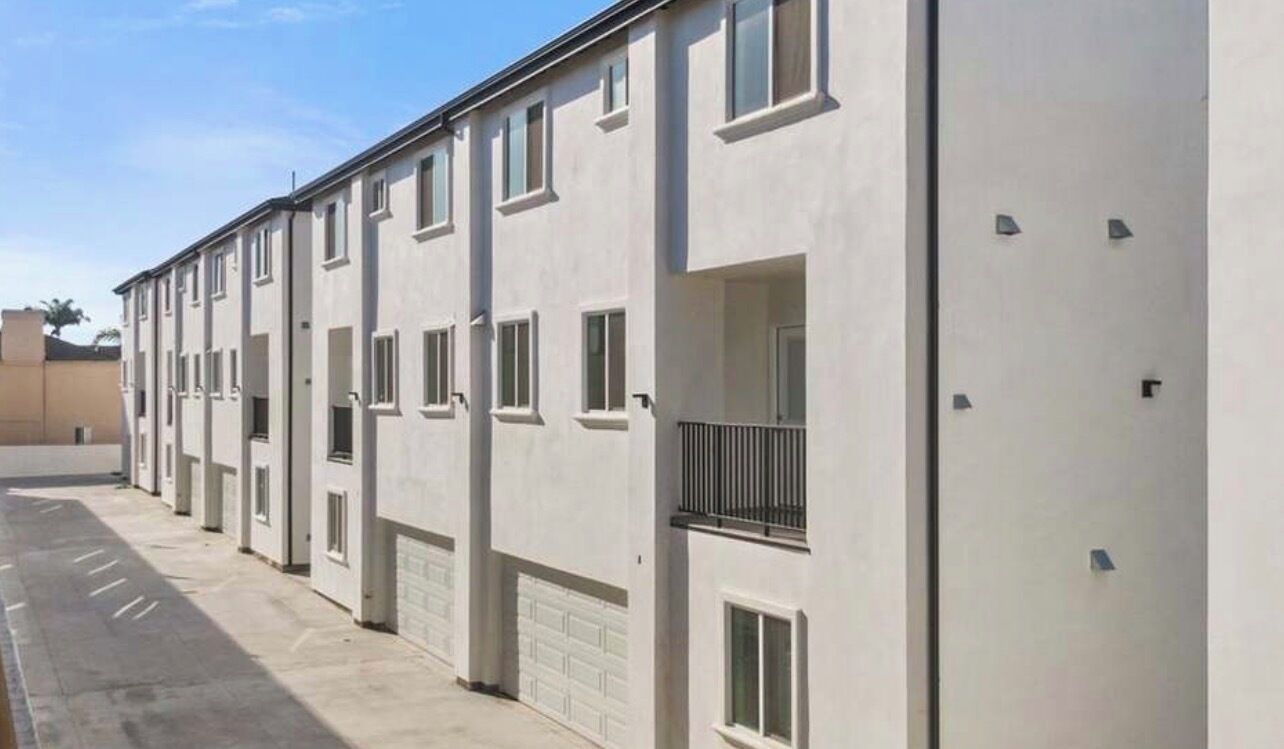 En række moderne, ensøjede bygninger med ensartet arkitektur, herunder altaner og garageporte.