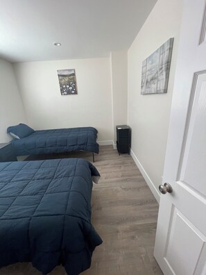 A bedroom with two beds, a door, and a small speaker. - Spacious 4-bedroom townhome in beautiful Hawthorne with AC (Hawthorne)
