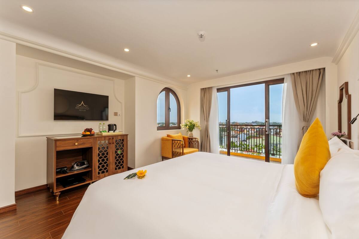 Een hotelkamer met een groot bed, een televisie, een bureau en een balkon met uitzicht.