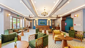 Eine Hotelhalle mit Sitzbereichen, einer Rezeption und einer Kandelaber.