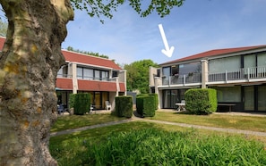 Ein Wohngebäude mit rotem Dach, großen Fenstern und einem Balkon.