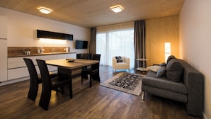 A modern kitchen with a dining area, a sofa, and a TV.