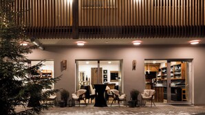 A building with a dining area, a Christmas tree, and a kitchen visible through the glass doors.