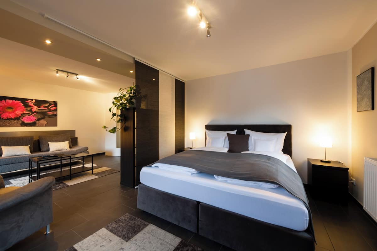 Un dormitorio moderno con una cama grande, un sofá, una mesita de centro y un cuadro en la pared.