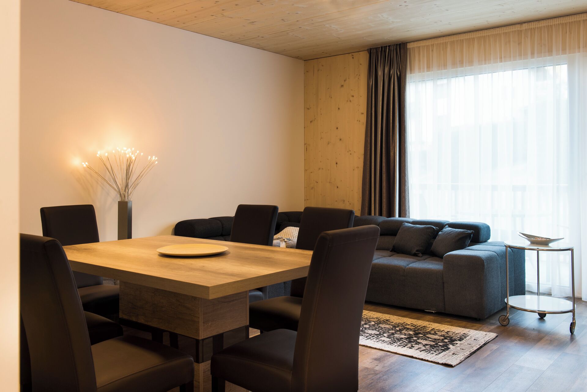 A modern living room with a dining table, sofa, and a small side table.