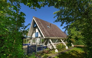 A house with a sloped roof, a fenced yard, and a swimming pool. - Holiday home Salvatorhoeve 120 nature house at Salvatorhoeve (Ouwerkerk)