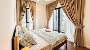 A bedroom with a large bed, beige curtains, a bedside lamp, and a view of the outside. - The Legacy OUG by Airhost (Kuala Lumpur)
