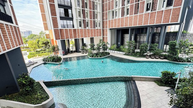 A modern building with a swimming pool, surrounded by greenery and a brick facade. - The Legacy OUG by Airhost (Kuala Lumpur)