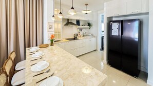 A modern kitchen with white cabinets, a black refrigerator, and a marble countertop. - The Legacy OUG by Airhost (Kuala Lumpur)