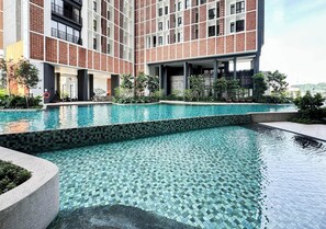 A modern building with a pool area, featuring a tiled pool and surrounding greenery. - The Legacy OUG by Airhost (Kuala Lumpur)