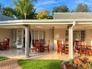A covered patio with a dining area, columns, and a tiled roof. - 19 On Bay Noakes (Harare)