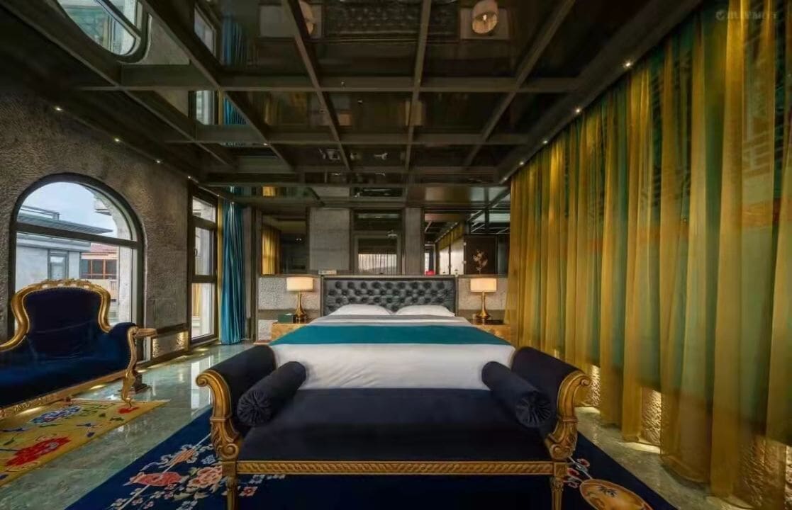 Habitación de hotel con una cama grande, un sofá, una araña y vistas a la ciudad.
