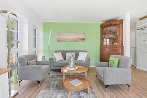 A living room with two grey sofas, a coffee table, a cabinet with glassware, and a painting on the wall. - Platzhirsch - New Platzhirsch vacation apartment in Greetsiel for relaxation (Krummhörn)