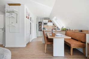 Una cocina moderna con comedor, un banco de madera y una mesa blanca.