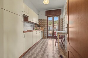 Une cuisine étroite avec des meubles blancs, un plan de travail en bois et un sol à motifs.