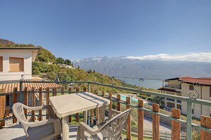 Een balkon met een tafel en stoelen, met uitzicht op een bergachtig landschap en een zwembadgedeelte op de achtergrond.