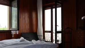 A wooden room with a bed, a chair, a window, and a dresser. - Cozy 90 sqm apartment in Tignale with pool, garden, terrace, parking and Wi-Fi (Aer)