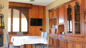 A dining area with a table, chairs, a television, and wooden cabinetry. - Cozy 90 sqm apartment in Tignale with pool, garden, terrace, parking and Wi-Fi (Aer)