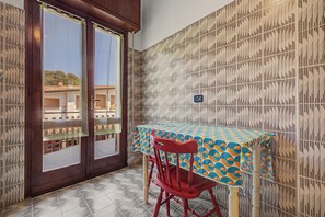 Une pièce avec une table et une chaise, un mur décoré de motifs et une porte donnant sur l’extérieur.