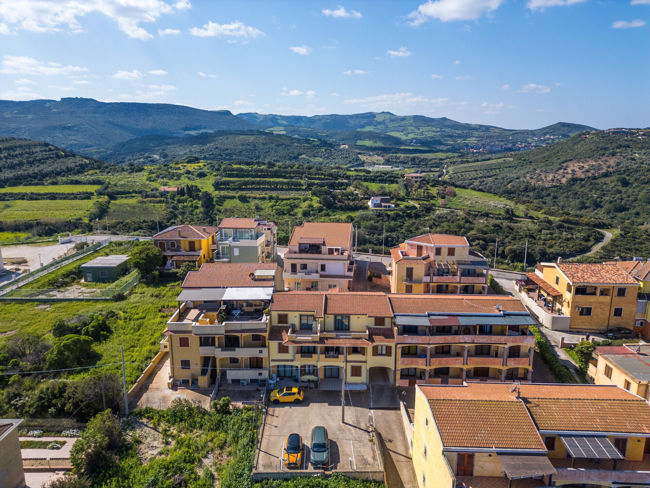 A residential area with terraced houses, a parking area, and a view of the surrounding hills.