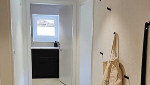 Ein Korridor mit Holzboden, einem kleinen Fenster und einem an der Wand befestigten Gepäckträger.