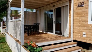 Ein Holzhaus mit überdachter Veranda, einem Esstisch und einer Schiebetür.