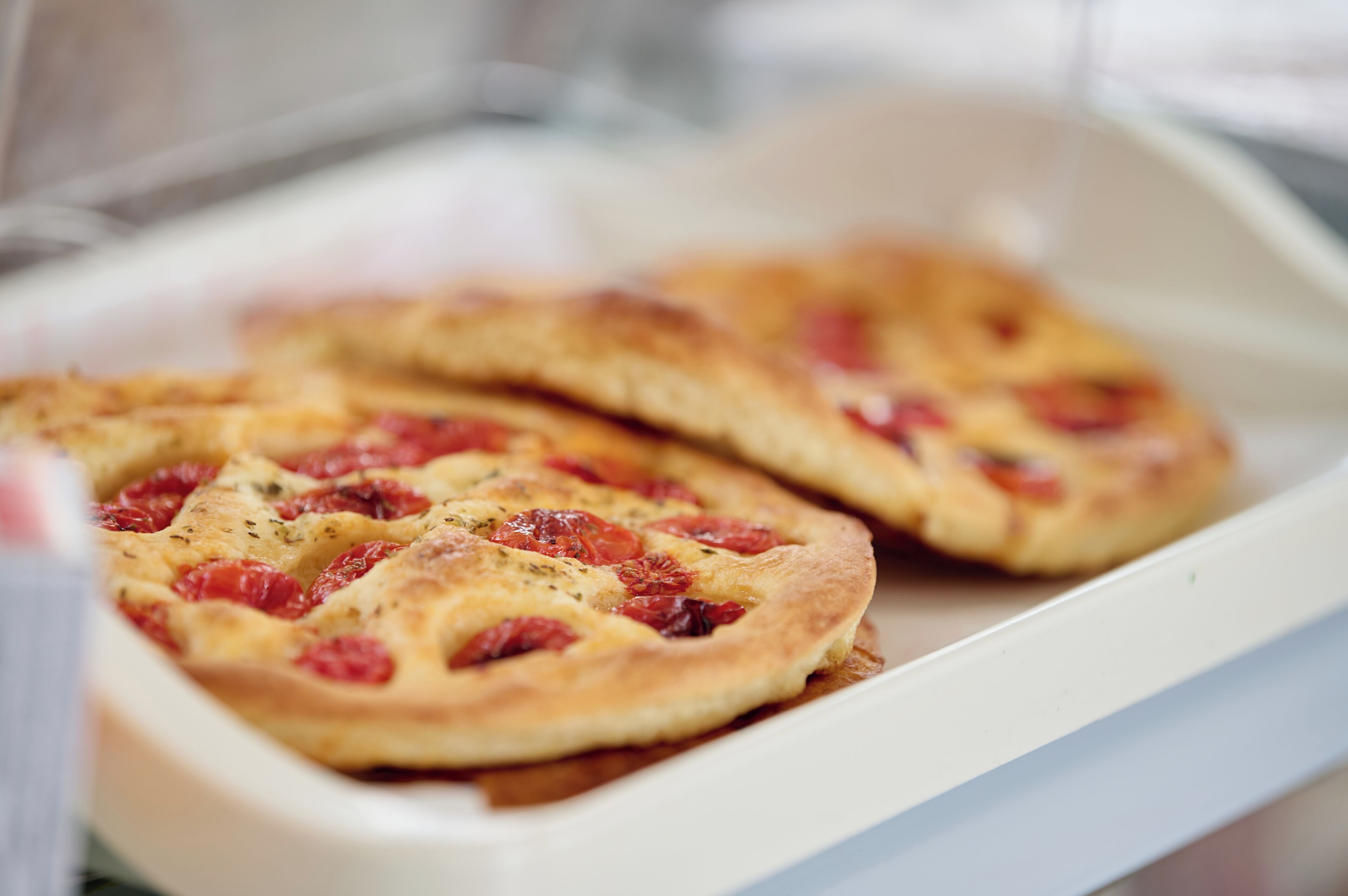 Una pizza con condimenti ben visibili in un contenitore bianco.