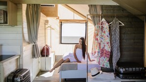 Ein Zimmer mit einem Bett, einem Koffer, einem Kleiderständer und einem Fenster.