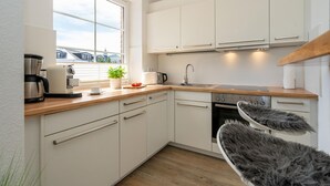 A modern kitchen with white cabinets, a coffee maker, a toaster, and a sink. - Syltliebe - Modern and central app. for 4 persons with balcony, car (Sylt)