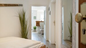A bedroom with a bed, a wooden headboard, a mirror, and a door leading to a bathroom. - Syltliebe - Modern and central app. for 4 persons with balcony, car (Sylt)