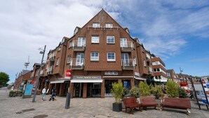 A multi-story building with a brick facade, balconies, and a Surf Shop sign. - Syltliebe - Modern and central app. for 4 persons with balcony, car (Sylt)