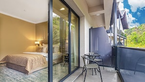 A bedroom with a bed, a glass door leading to a balcony, and a small table with chairs. - Davo Hotel (Târgu Neamț)
