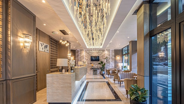 A modern hotel lobby with a reception desk, seating area, and a large chandelier. - Davo Hotel (Târgu Neamț)