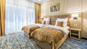 A hotel room with two beds, a large window with curtains, a painting on the wall, and a nightstand with a lamp. - Davo Hotel (Târgu Neamț)