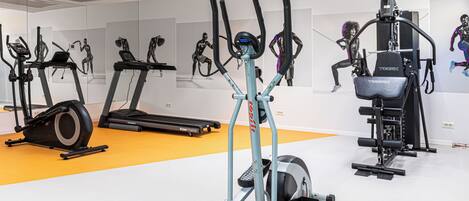 Una palestra con diverse attrezzature per esercizi, tra cui tapis roulant, ellittica e macchina per pesi.