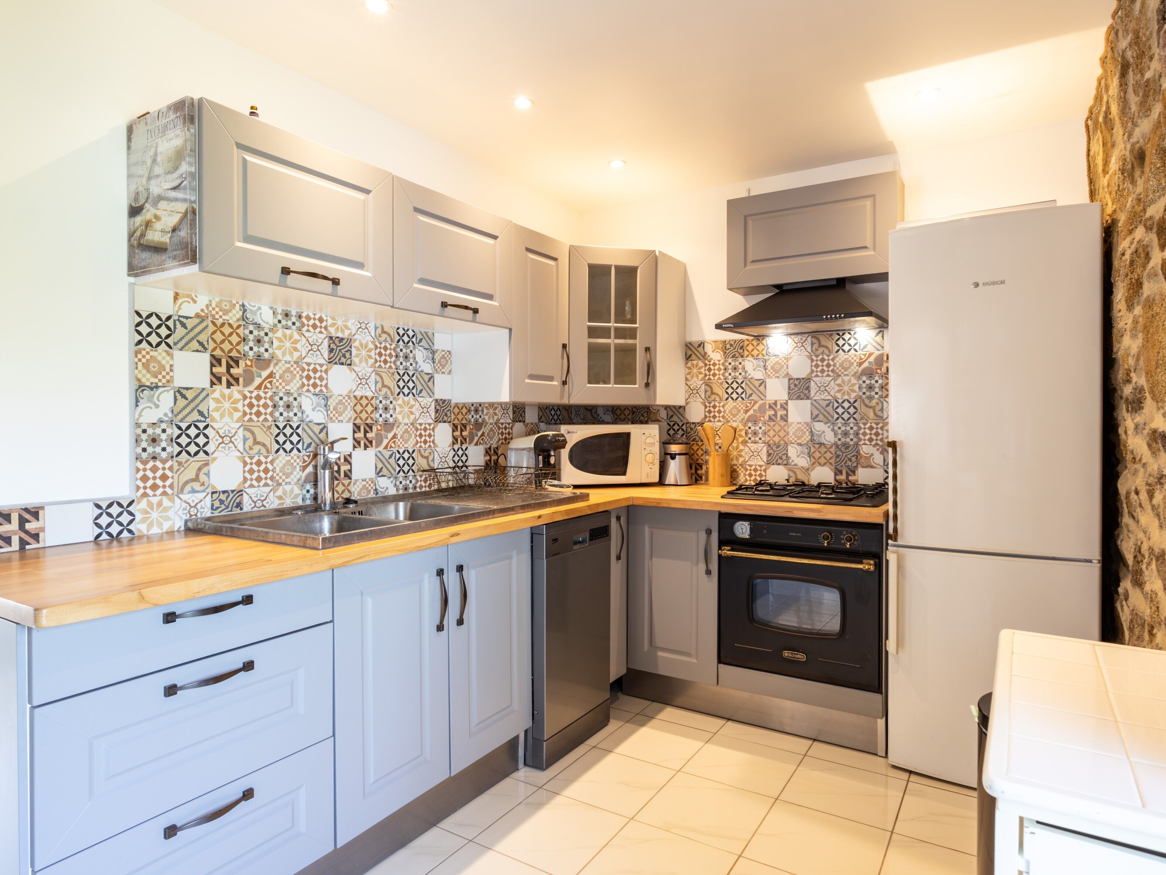 Una cocina moderna con armarios blancos, microondas, estufa y refrigerador.