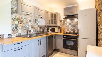 Una cocina moderna con armarios blancos, microondas, estufa y refrigerador.