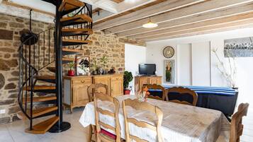 Un interior rústico con una escalera espiral, muebles de madera, paredes de piedra y un comedor.
