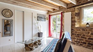 Un intérieur moderne avec un mur en pierre, des poutres en bois au plafond, une table en verre et un canapé.