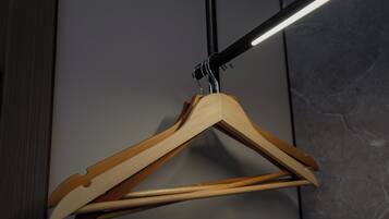 A wooden hanger with a metal hook against a grey wall.