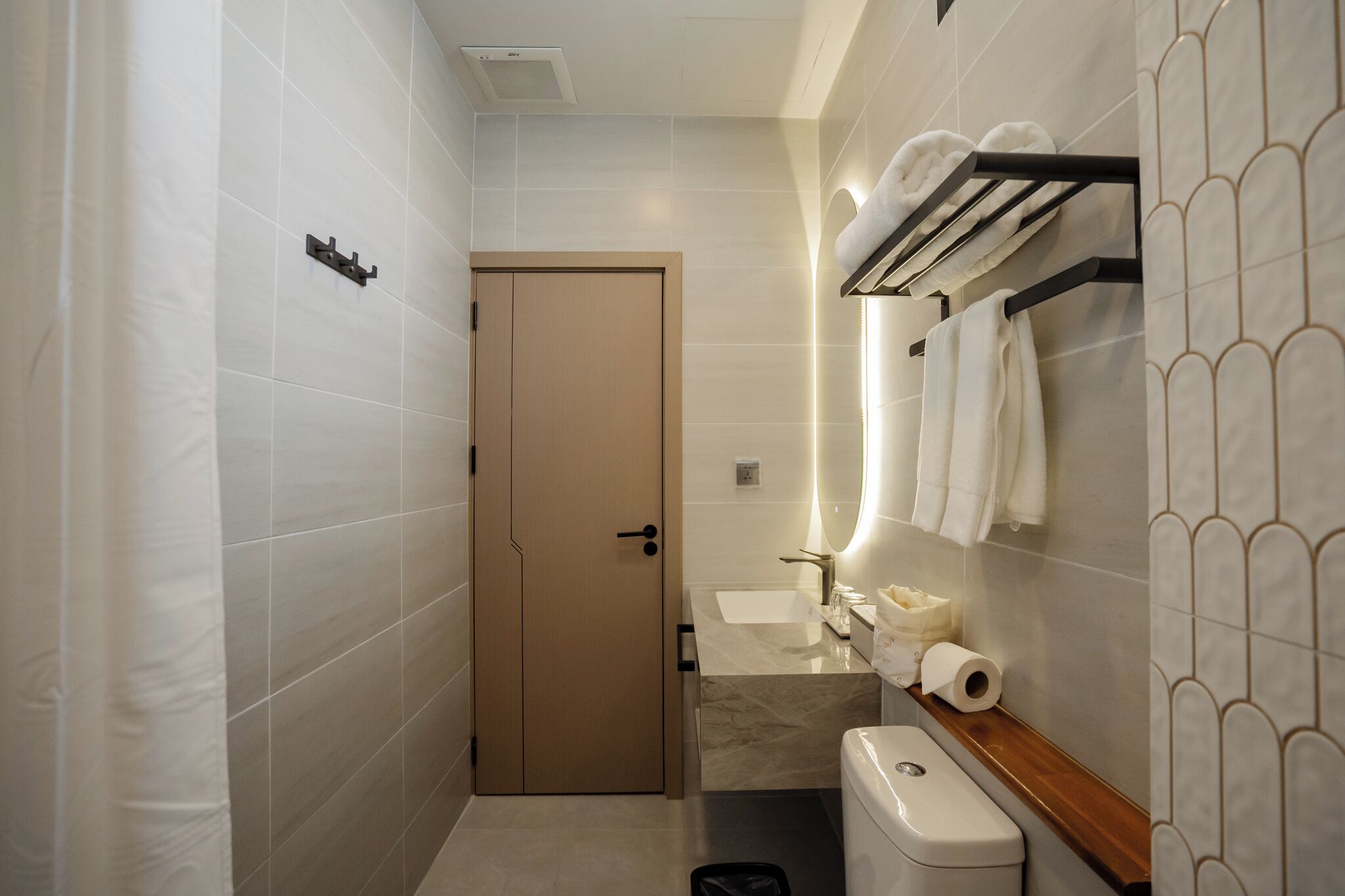 A bathroom with a toilet, sink, towel rack, and shower curtain.