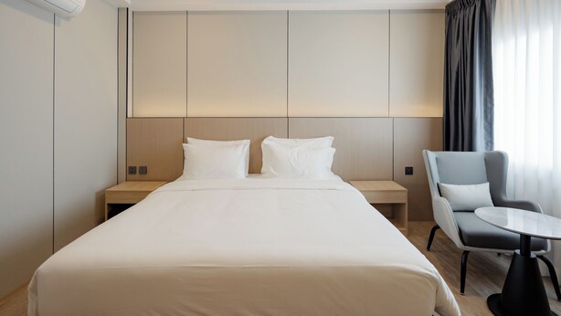 A hotel room with a large bed, bedside tables, a chair, and a small table. - HippoTel Khaorang Phuket Town (Phuket)